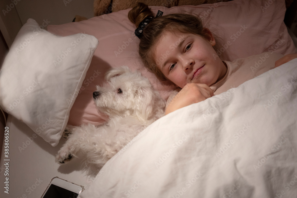 Cute girl lying down by dog in bedroom Cute girl lying down by dog in bedroom