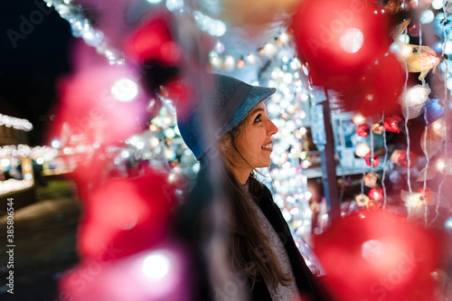 Smiling woman watching a stand on fairground at night