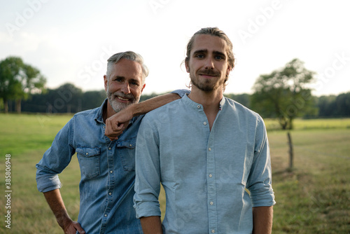 Portrait of happy father with adult son on a meadow in the countryside photo