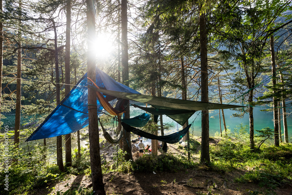 Tent and hammock hanging on trees growing on shore of Blindsee lake Tent and hammock hanging on trees growing on shore of Blindsee lake