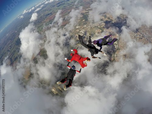 Skydiving 4 way team above the clouds. Teamwork and focus.