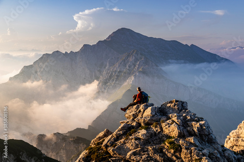 Hiker sitting on mountain peak at Bergamasque Alps, Italy