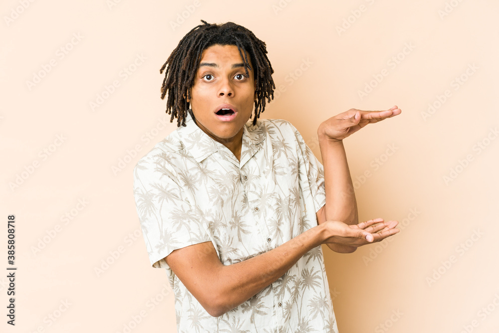 Young african american rasta man shocked and amazed holding a copy space between hands. Young african american rasta man shocked and amazed holding a copy space between hands.