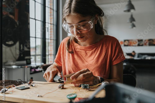 teenage girl tinkering with soldering iron at home