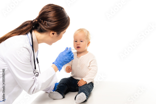 Selective focus of doctor holding stick near toddler boy isolated on white