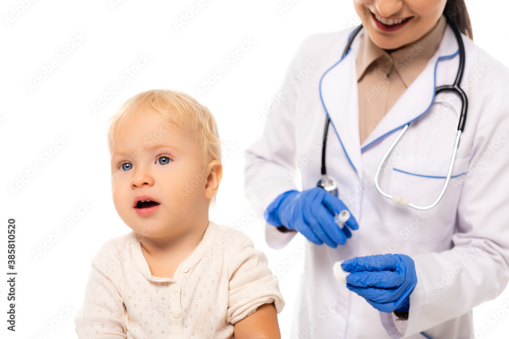 Selective focus of toddler boy near pediatrician with cotton and syringe isolated on white Selective focus of toddler boy near pediatrician with cotton and syringe isolated on white