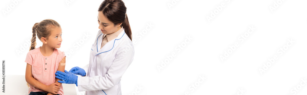 Panoramic shot of doctor in latex gloves touching hand of girl with patch isolated on white Panoramic shot of doctor in latex gloves touching hand of girl with patch isolated on white