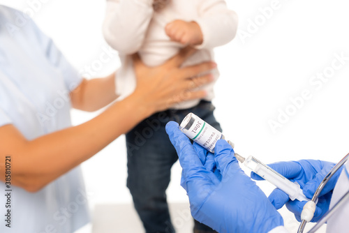 Selective focus of pediatrician holding syringe and vaccine near father and child isolated on white