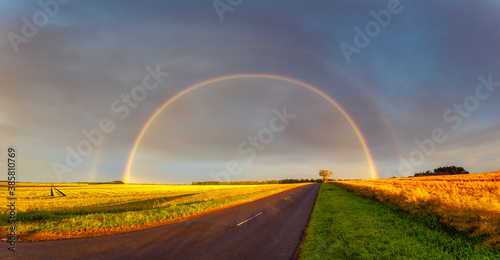 Double rainbow arching over empty countryside highway