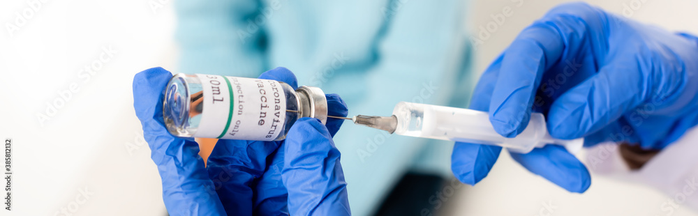 Panoramic crop of doctor in latex gloves holding syringe and vaccine with coronavirus lettering isolated on white - obrazy, fototapety, plakaty 