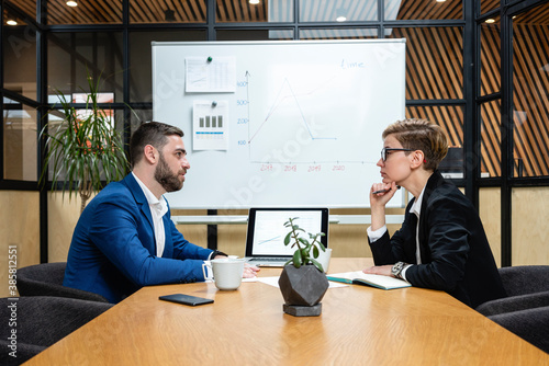 Confident businesswoman listening while looking at executive during job interview in board room