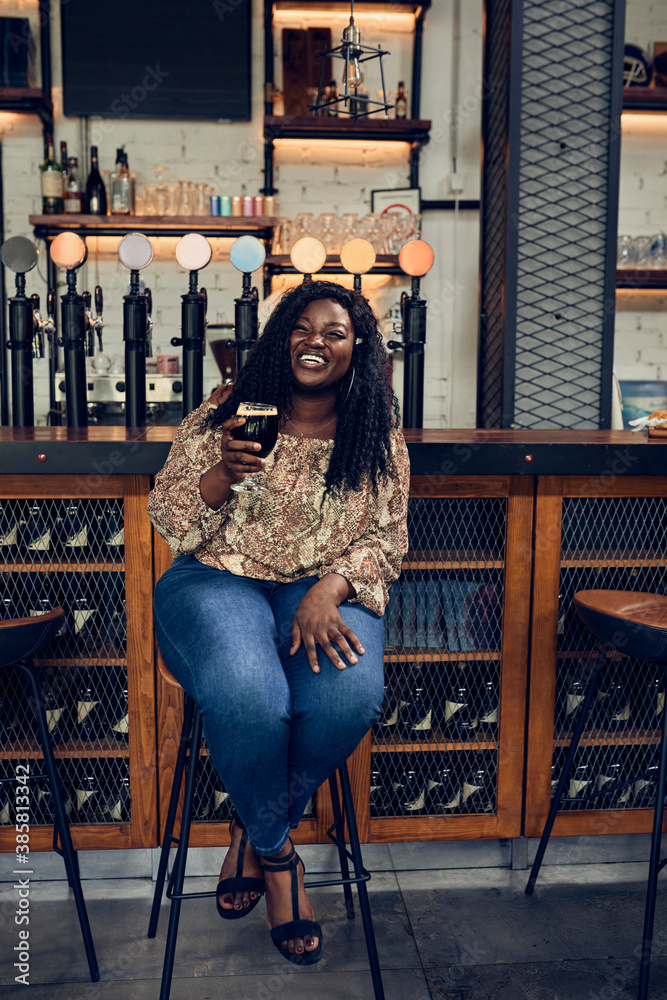 Happy woman sitting at the counter in a pub having a beer Happy woman sitting at the counter in a pub having a beer