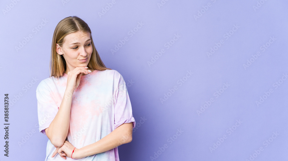 Young blonde woman isolated on purple background looking sideways with doubtful and skeptical expression. Young blonde woman isolated on purple background looking sideways with doubtful and skeptical expression.