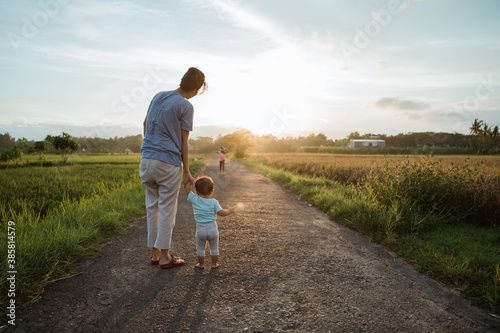 Slika na platnu mother help her baby to walk her first step on country road