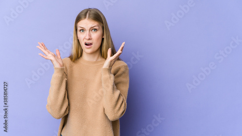 Young blonde woman isolated on purple background surprised and shocked.