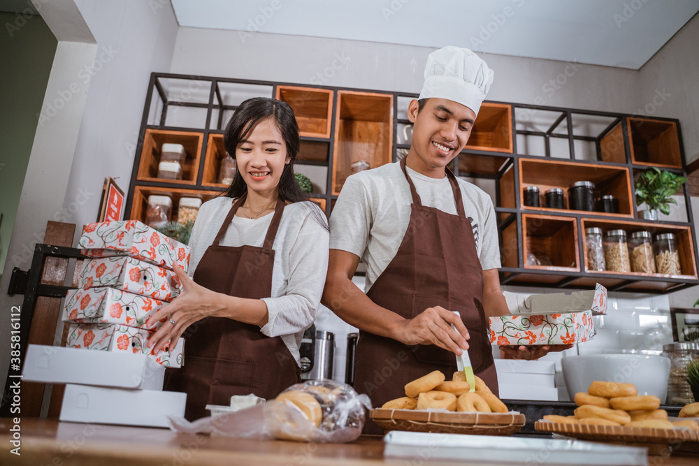 Young couples making bakery donuts in the kitchen at the bakery shop as business ownership entrepreneurs Young couples making bakery donuts in the kitchen at the bakery shop as business ownership entrepreneurs