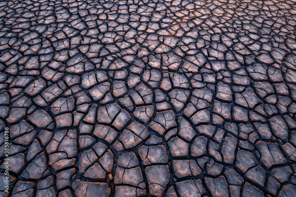 View of cracked mud tiles in dry reservoir during sunset