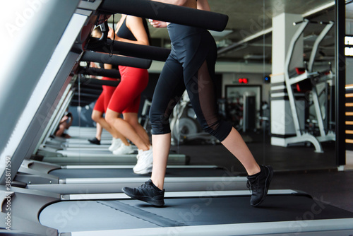 Fit young women running together on treadmill