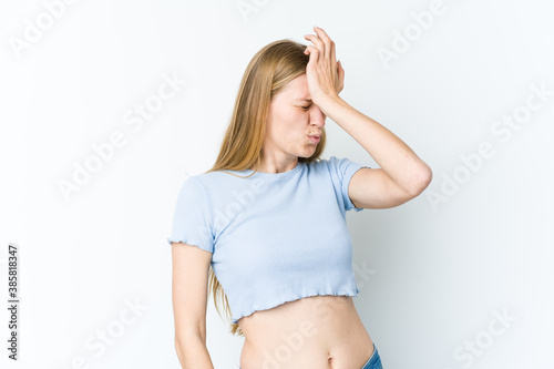 Young blonde woman isolated on white background forgetting something, slapping forehead with palm and closing eyes. © Asier