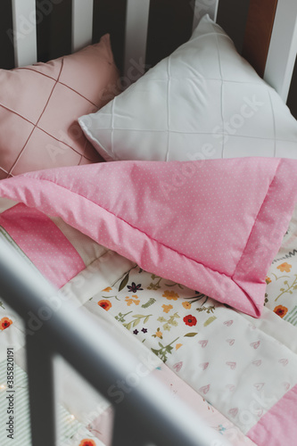Cozy baby cot with pink patchwork blanket. Baby bedding. Baby crib, close up. Textile for children nursery. Nap and sleep time © paralisart