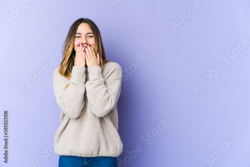 Young caucasian woman isolated on purple background laughing about something, covering mouth with hands.