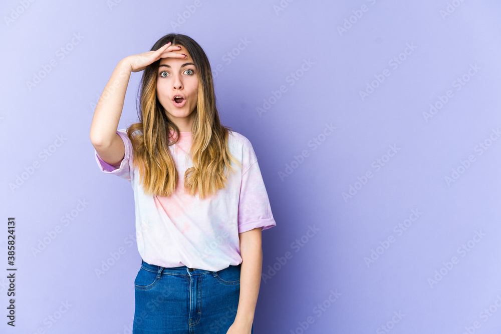 Young caucasian woman isolated on purple background looking far away keeping hand on forehead. Young caucasian woman isolated on purple background looking far away keeping hand on forehead.