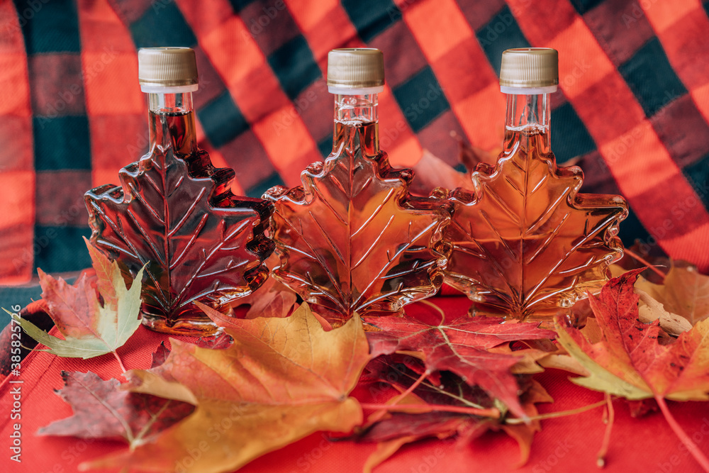 Maple syrup bottles at Quebec sugar shack house with red autumn leaves
