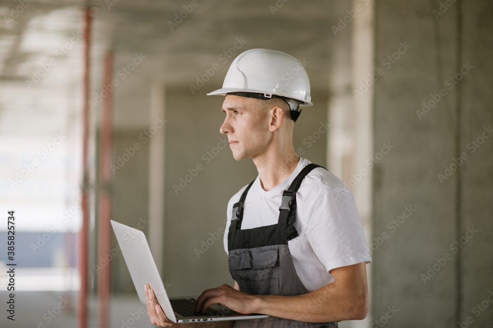 Worker in hard hat working on laptop Worker in hard hat working on laptop