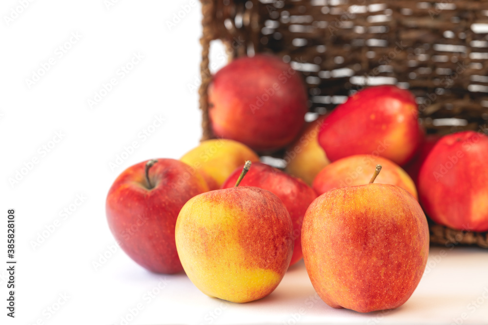 Red apples close up. Fresh organic fruits in a wicker basket isolated on white background with copy space. Red apples close up. Fresh organic fruits in a wicker basket isolated on white background with copy space.