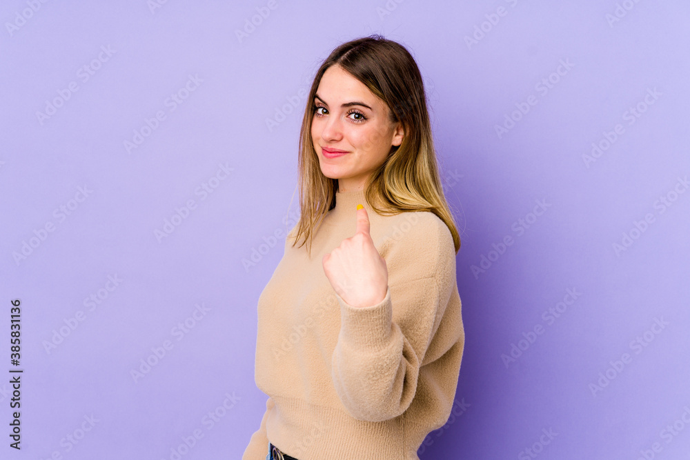 Young caucasian woman isolated on purple background pointing with finger at you as if inviting come closer. Young caucasian woman isolated on purple background pointing with finger at you as if inviting come closer.