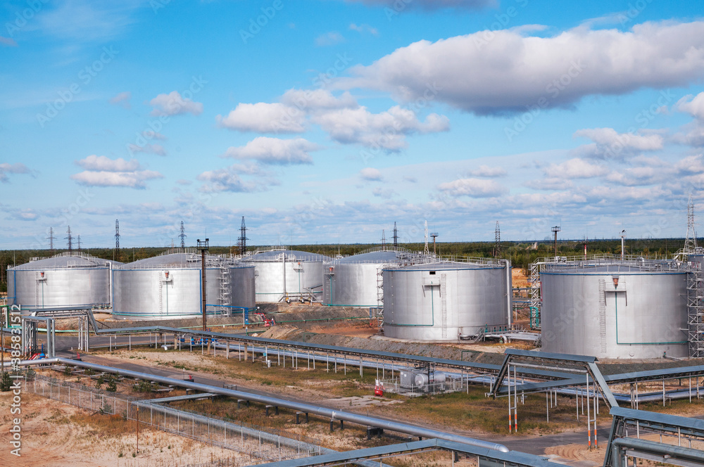 Cloudy day. Tanks with oil for further transportation of oil through pipes at an oil refinery and oil pumping station Cloudy day. Tanks with oil for further transportation of oil through pipes at an oil refinery and oil pumping station