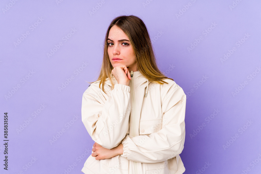 Young caucasian woman isolated on purple background suspicious, uncertain, examining you. Young caucasian woman isolated on purple background suspicious, uncertain, examining you.