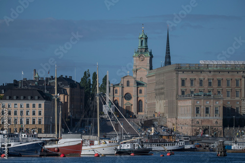 Boats at the jetties at the bridge between Blasieholmen and Skeppsholmen in Stockholm a sunny summer morning, old houses, the church Storkyrkan and the Royal Castle in the old town photo