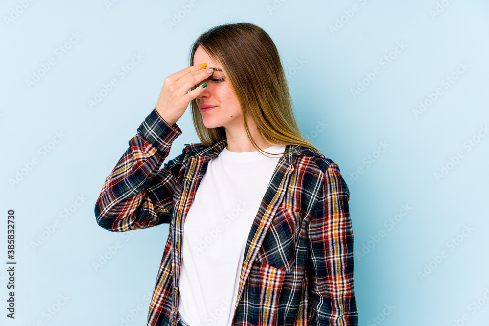 Young caucasian woman isolated on blue background having a head ache, touching front of the face. Young caucasian woman isolated on blue background having a head ache, touching front of the face.