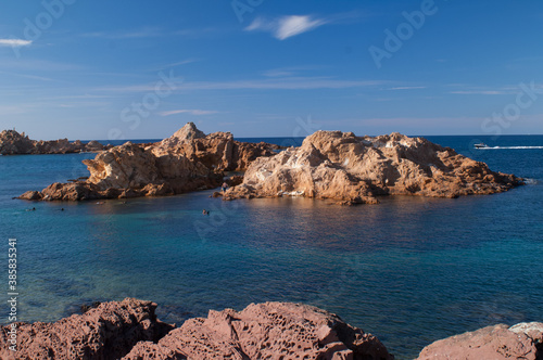 Brown-orange rocks in the sea with blue sky in the background