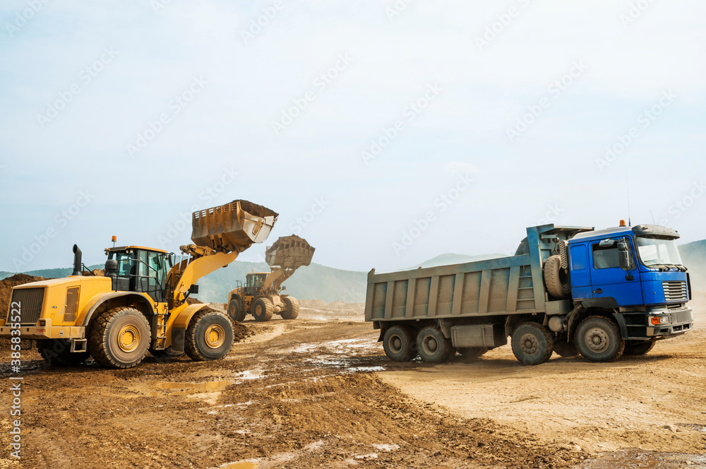 Obraz premium Wheel loader loads clay into the bucket of a dump truck