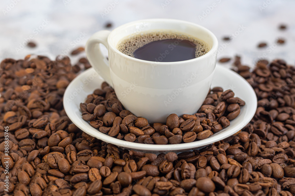 A cup of delicious aromatic coffee. It is placed on a substrate made of coffee beans. New Year holiday concept. On a light background. A cup of delicious aromatic coffee. It is placed on a substrate made of coffee beans. New Year holiday concept. On a light background.