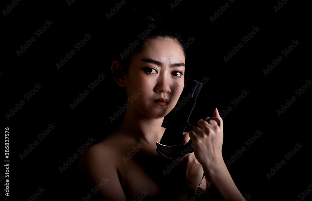 Portrait beautiful Asia woman one hand holding a gun and karambit knife at the black background Portrait beautiful Asia woman one hand holding a gun and karambit knife at the black background