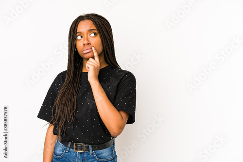 Young african american woman isolated on white background looking sideways with doubtful and skeptical expression. © Asier