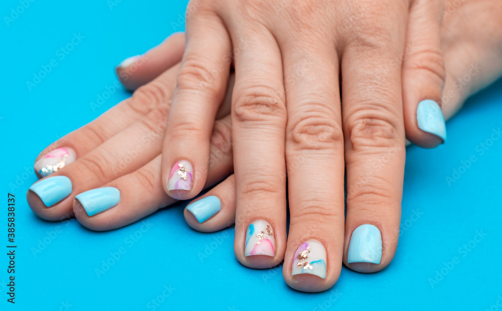 Woman's hands with beautiful manicure on blue background.