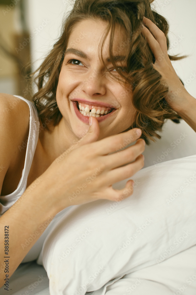 Portrait of young beautiful girl with blanket on white background. At home. Comfort. Healthy lifestyle, clear skin. Curly hair. Emotions. About sleeping and awakening. Portrait of young beautiful girl with blanket on white background. At home. Comfort. Healthy lifestyle, clear skin. Curly hair. Emotions. About sleeping and awakening.