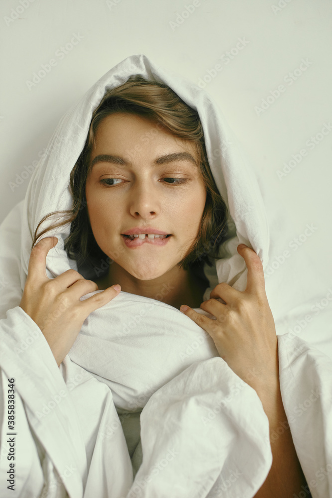 Portrait of young beautiful girl with blanket on white background. At home. Comfort. Healthy lifestyle, clear skin. Curly hair. Emotions. About sleeping and awakening. Portrait of young beautiful girl with blanket on white background. At home. Comfort. Healthy lifestyle, clear skin. Curly hair. Emotions. About sleeping and awakening.