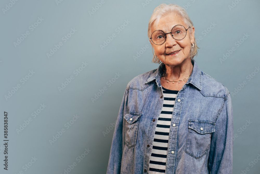Φωτογραφία Cheerful lovely old woman with nice jewelry, straight short haircut, smart style posing isolated over blue background and smiling