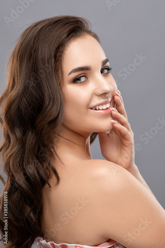 Portrait of brunette girl with curly hair healthy clean skin and fresh make-up. Looking into the camera. Aesthetic cosmetology and makeup concept.