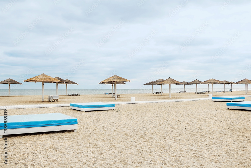 Beautiful beach on the seashore. Lots of sun umbrellas. Sun loungers on the beach. Beach chairs and large umbrellas. Clean beach without people. Summer vacation at the sea.