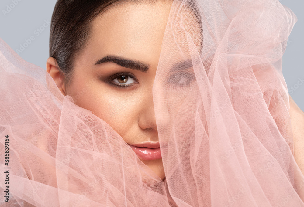 Portrait of a charming girl with delicate makeup, lush eyebrows with a cloth near the face. Looking into the camera. Personal care, cosmetology and makeup concept. Portrait of a charming girl with delicate makeup, lush eyebrows with a cloth near the face. Looking into the camera. Personal care, cosmetology and makeup concept.