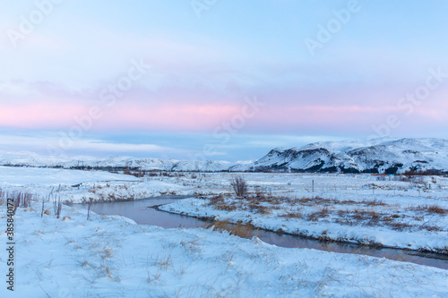 River on the plain in Iceland. The banks are covered with snow. Winter landscape, open spaces. © Kate