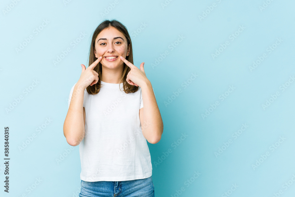 Young caucasian woman smiles, pointing fingers at mouth. Young caucasian woman smiles, pointing fingers at mouth.
