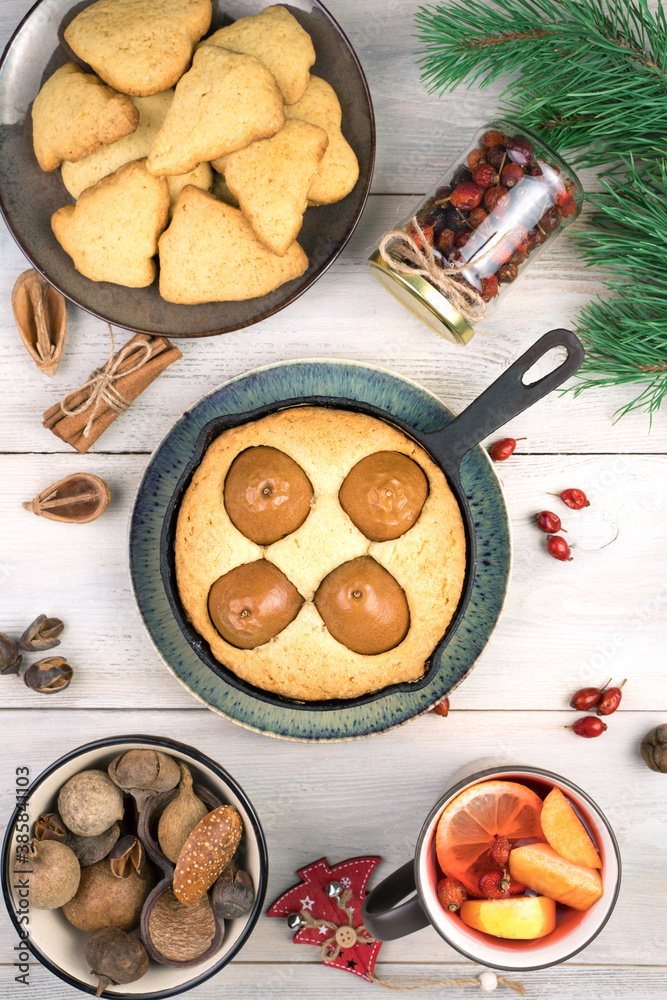 Festive table with pastries and pine branches on a light wooden background. Top view, vertical orientation. Concept of holiday backgrounds. Festive table with pastries and pine branches on a light wooden background. Top view, vertical orientation. Concept of holiday backgrounds.
