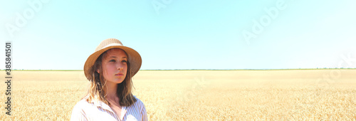 Portrait of young teenage girl standing in a wheat field over blue sky background. Young girl outdoors. 